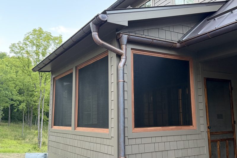 Copper gutters and downspouts over screened porch windows with cedar shingle siding on a custom home by Wiley Construction