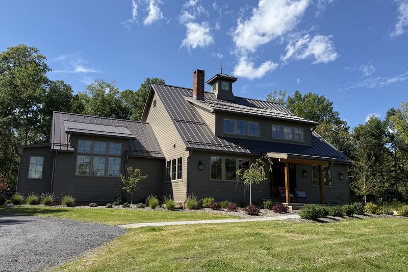 Front elevation of a custom home by Wiley Construction with a standing seam metal roof, cupola and timber front porch