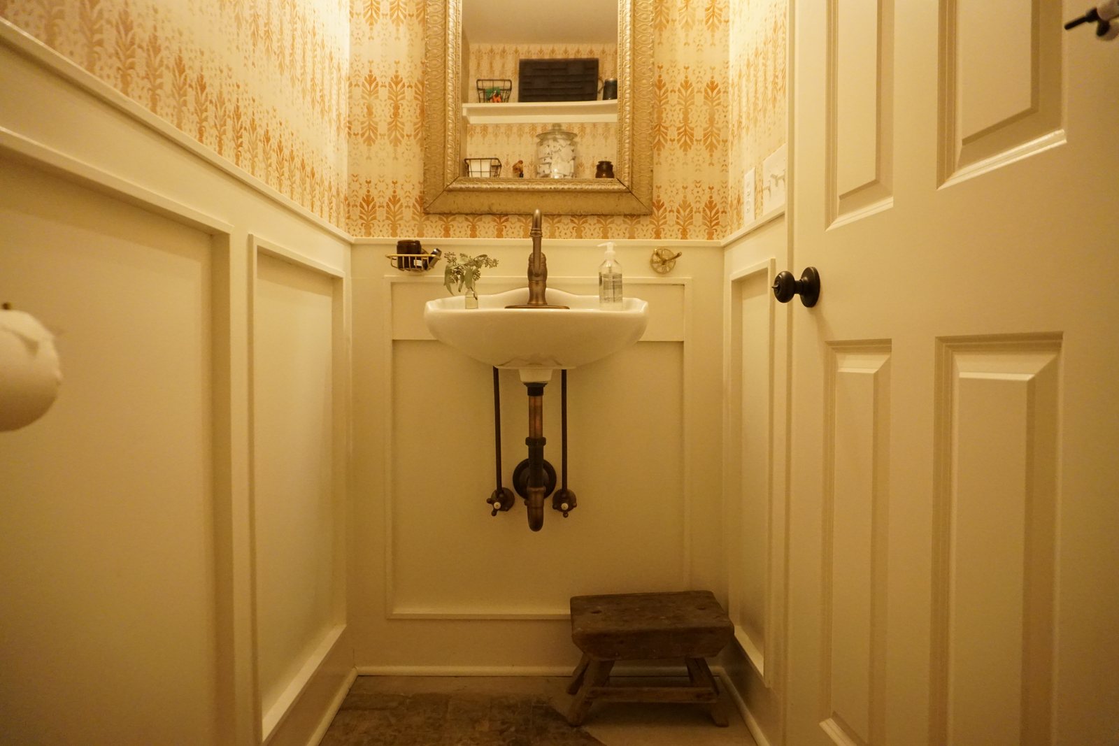 Powder room with painted wainscoting, gold patterned wallpaper and reclaimed hearth brick set into the floor: 1790 Farmhouse Renovation, Milton NY